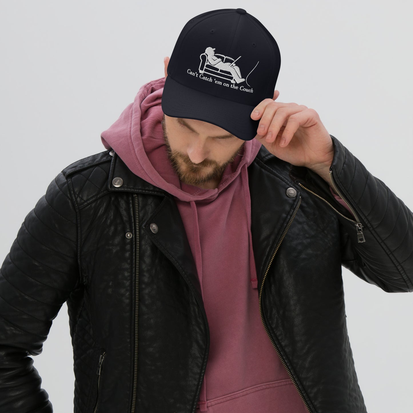Man wearing navy dad hat with fishing couch design, maroon hoodie and leather jacket