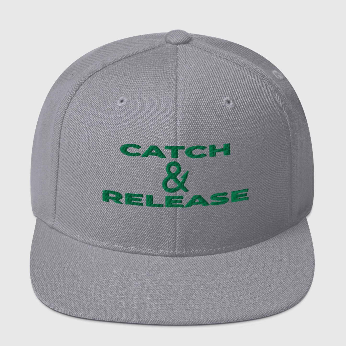 Silver snapback cap with bold green "Catch & Release" text