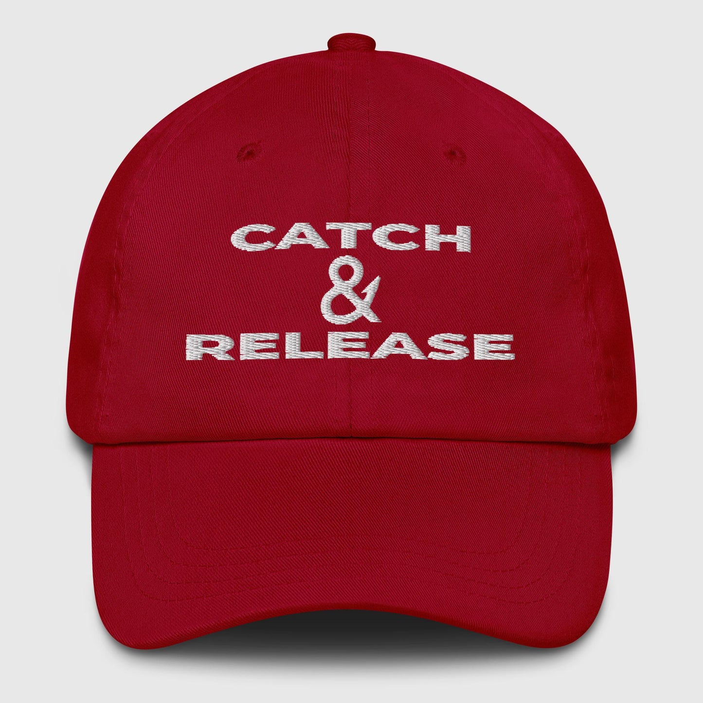 Red dad hat with bold white “Catch & Release” embroidered slogan