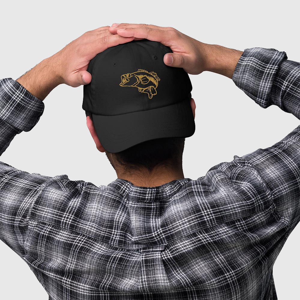 Person wearing black dad hat with embroidered largemouth bass design in gold thread, backwards view