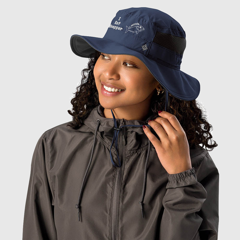 Woman wearing navy Columbia bucket hat with embroidered “I Eat Snapper” text and fish design