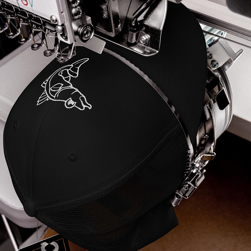 Black retro trucker cap with white snook fish logo being embroidered on a machine