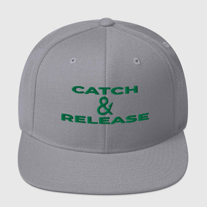Silver snapback fishing hat with green "Catch & Release" text and flat brim. - Catch & Release Snapback