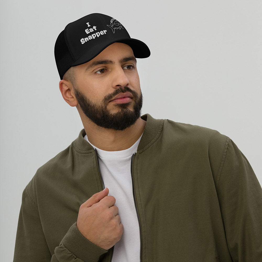 Man wearing black mesh back trucker cap with white “I Eat Snapper” text and fish embroidery