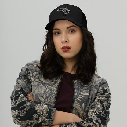 Black trucker fishing hat with white fish graphic, worn with patterned jacket. - Snook – Fish Series Trucker Cap